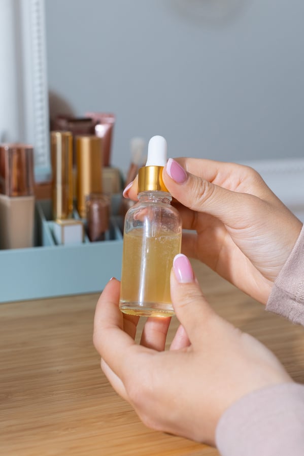 Person's Hands Holding a Bottle of Skincare